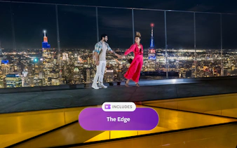 Couple enjoying night view from Edge Observation Deck, New York City skyline in background.