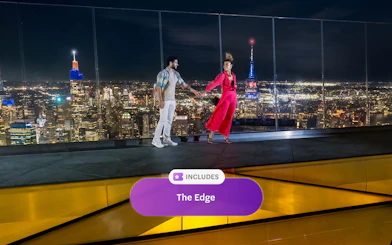 Couple enjoying night view from Edge Observation Deck, New York City skyline in background.