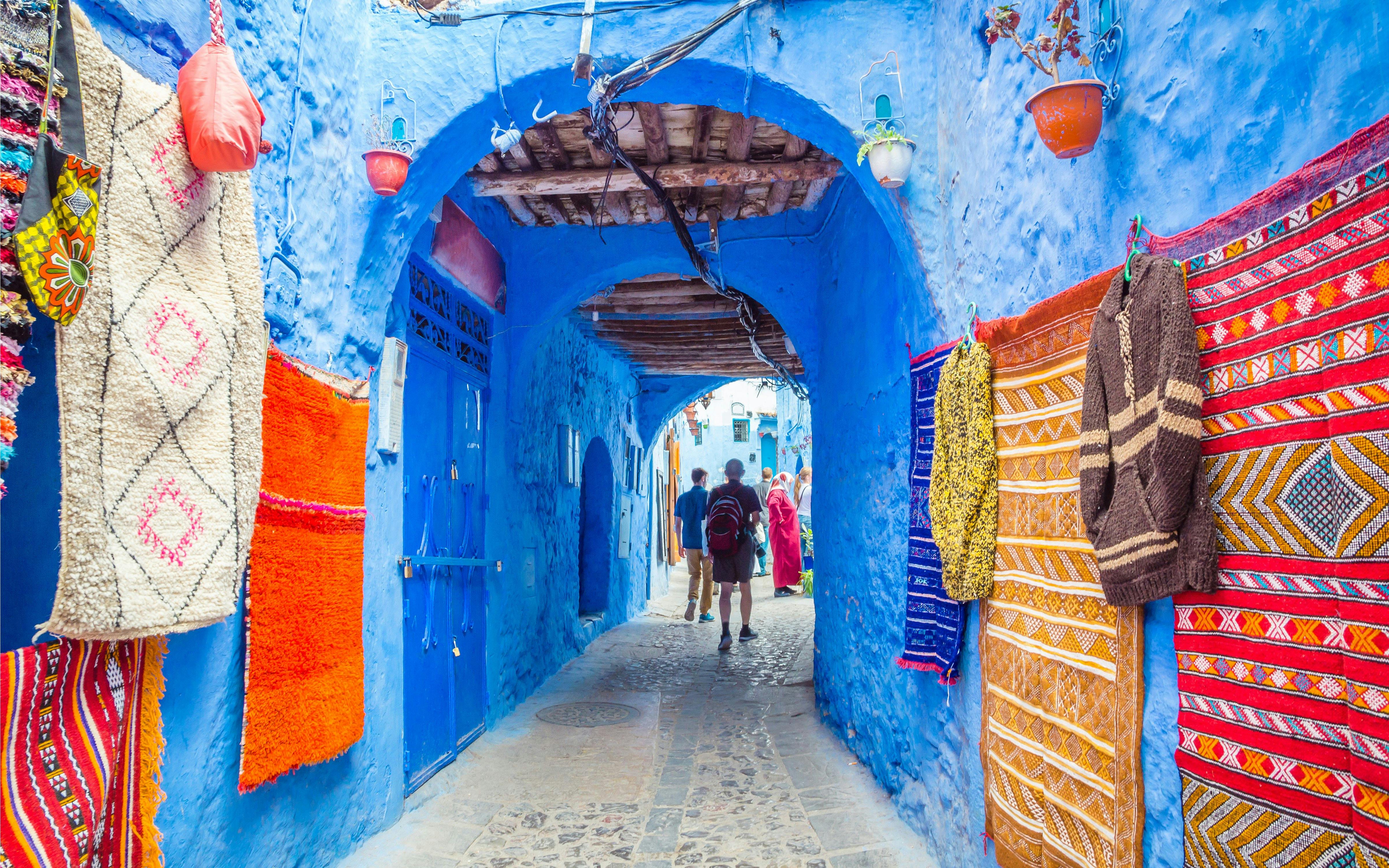 Street market with colorful textiles in blue medina of Chefchaouen, Morocco.