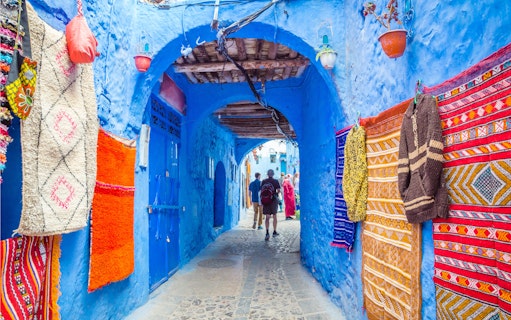 Street market with colorful textiles in blue medina of Chefchaouen, Morocco.