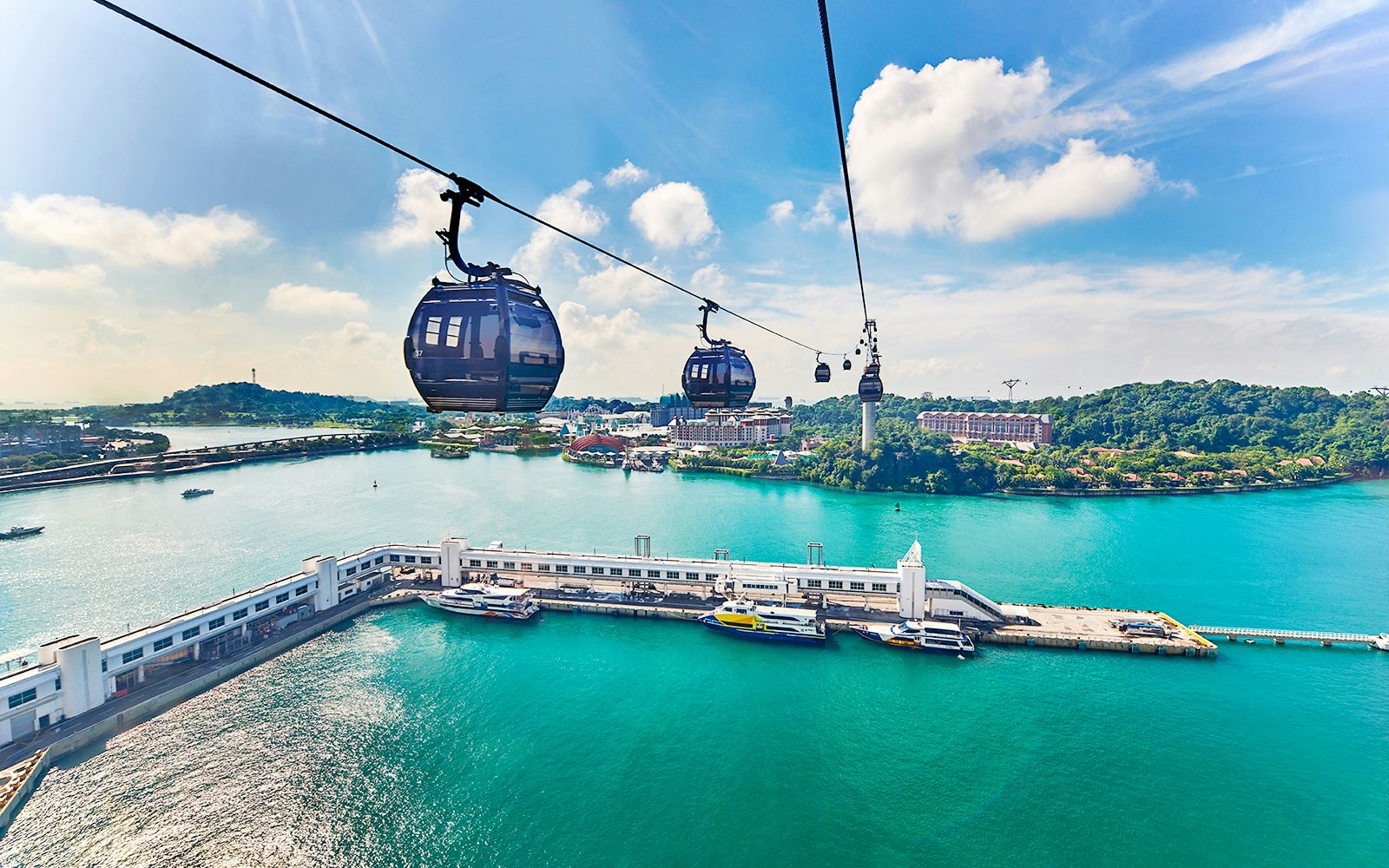 Cable cars over water with view of Sentosa Island, Singapore.