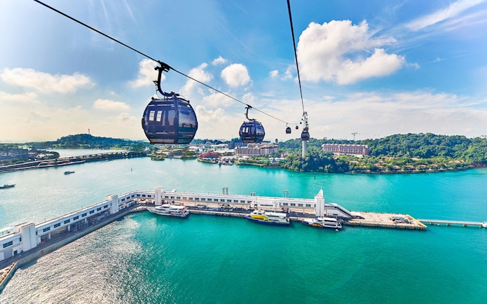 Cable cars over water with view of Sentosa Island, Singapore.
