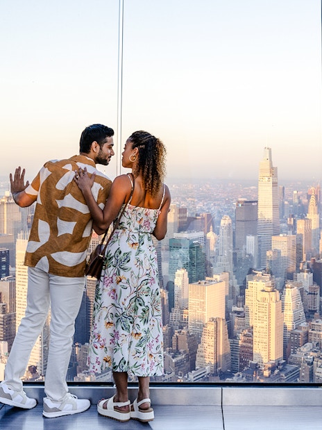Couple enjoying sunset view from The Edge, New York City skyline in background.