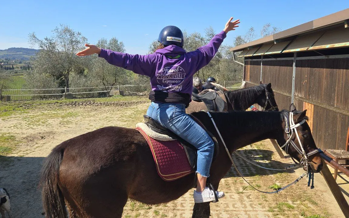 Horseback rider in Tuscany countryside with view of San Gimignano in the background.