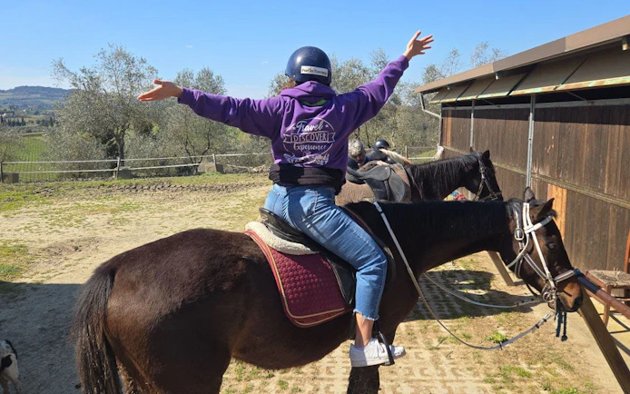 Horseback rider in Tuscany countryside with view of San Gimignano in the background.