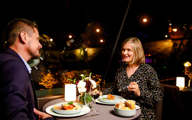 Couple dining on Seine River cruise with Paris lights in background.