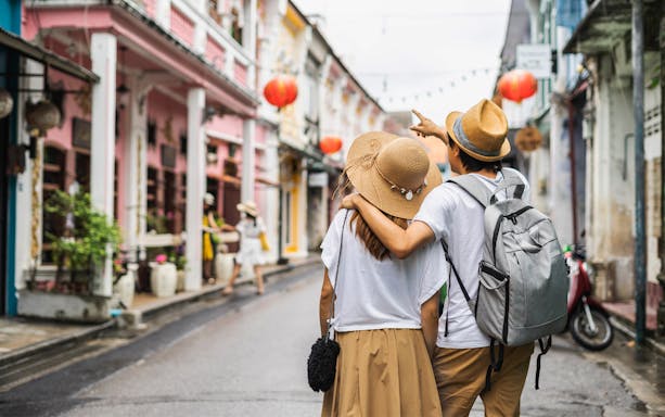 Young couple walking through old town street with shops and red lanterns.