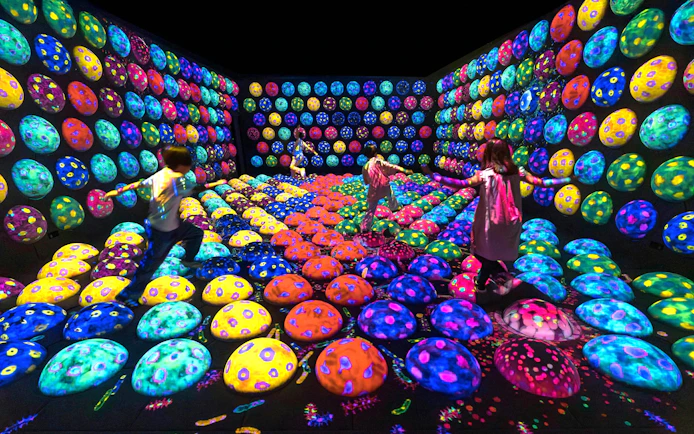 Children exploring colorful interactive art installation at teamLab Biovortex Kyoto.