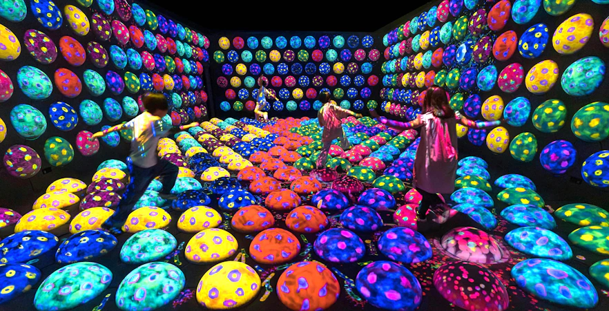 Children exploring colorful interactive art installation at teamLab Biovortex Kyoto.