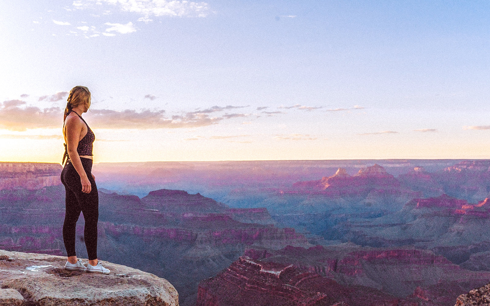 Person standing at Grand Canyon South Rim during sunset.