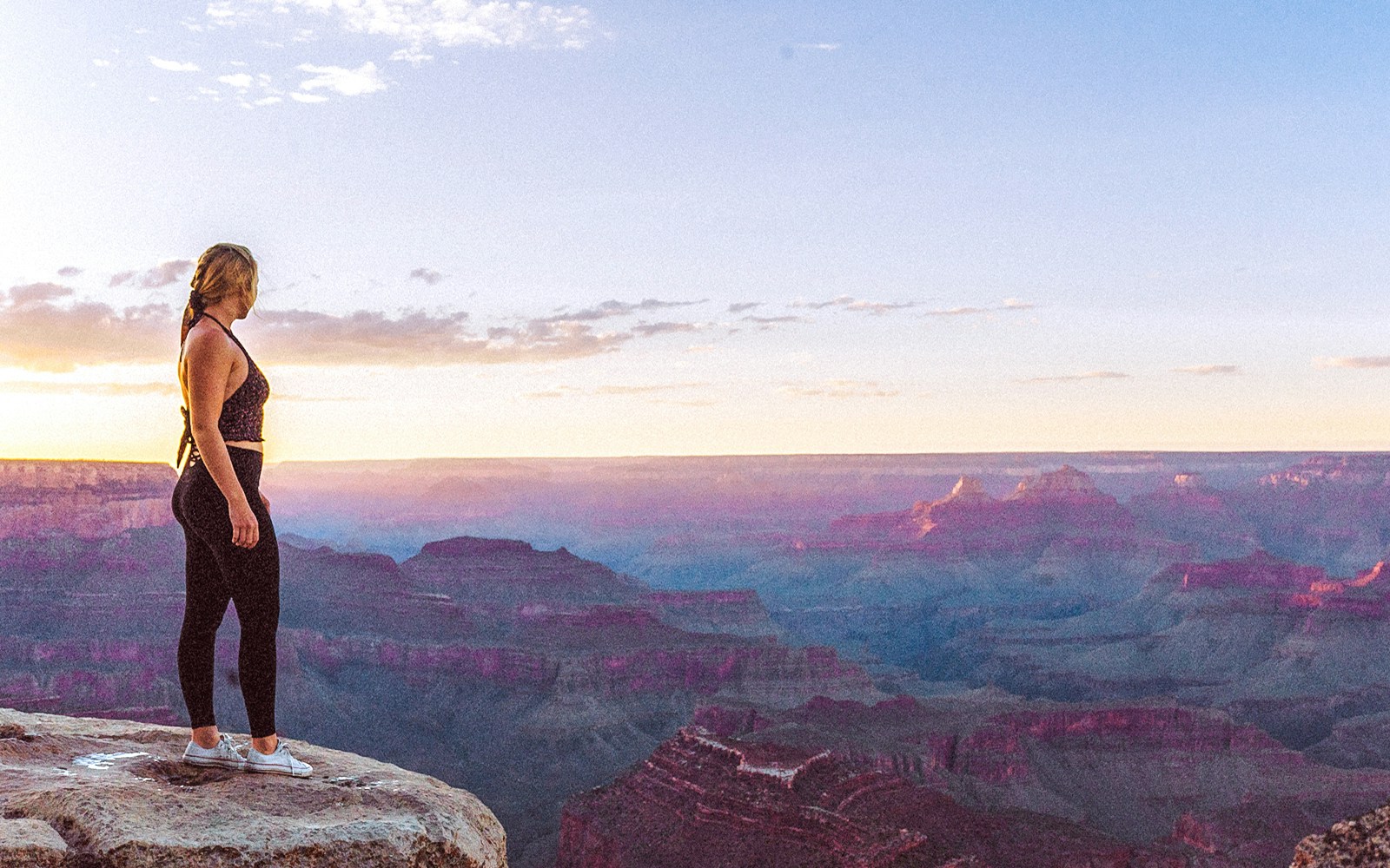 Person standing at Grand Canyon South Rim during sunset.