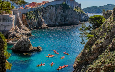 Kayakers exploring the clear waters near Dubrovnik's historic city walls.
