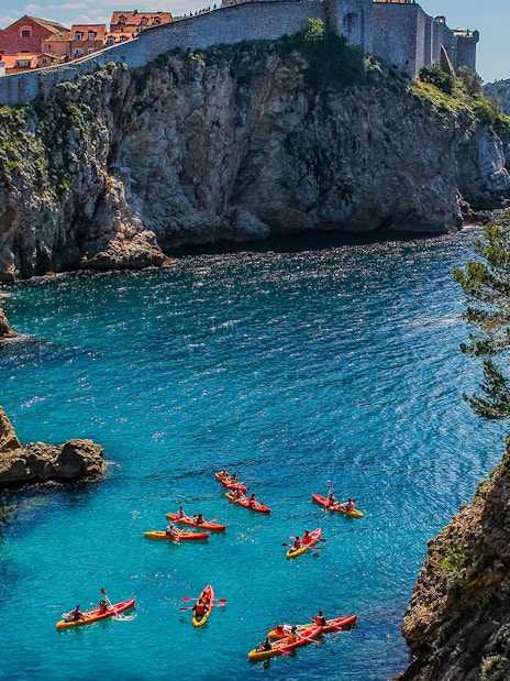 Kayakers exploring the clear waters near Dubrovnik's historic city walls.