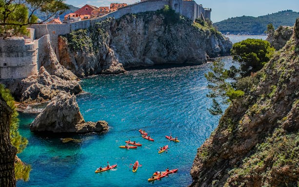 Kayakers exploring the clear waters near Dubrovnik's historic city walls.