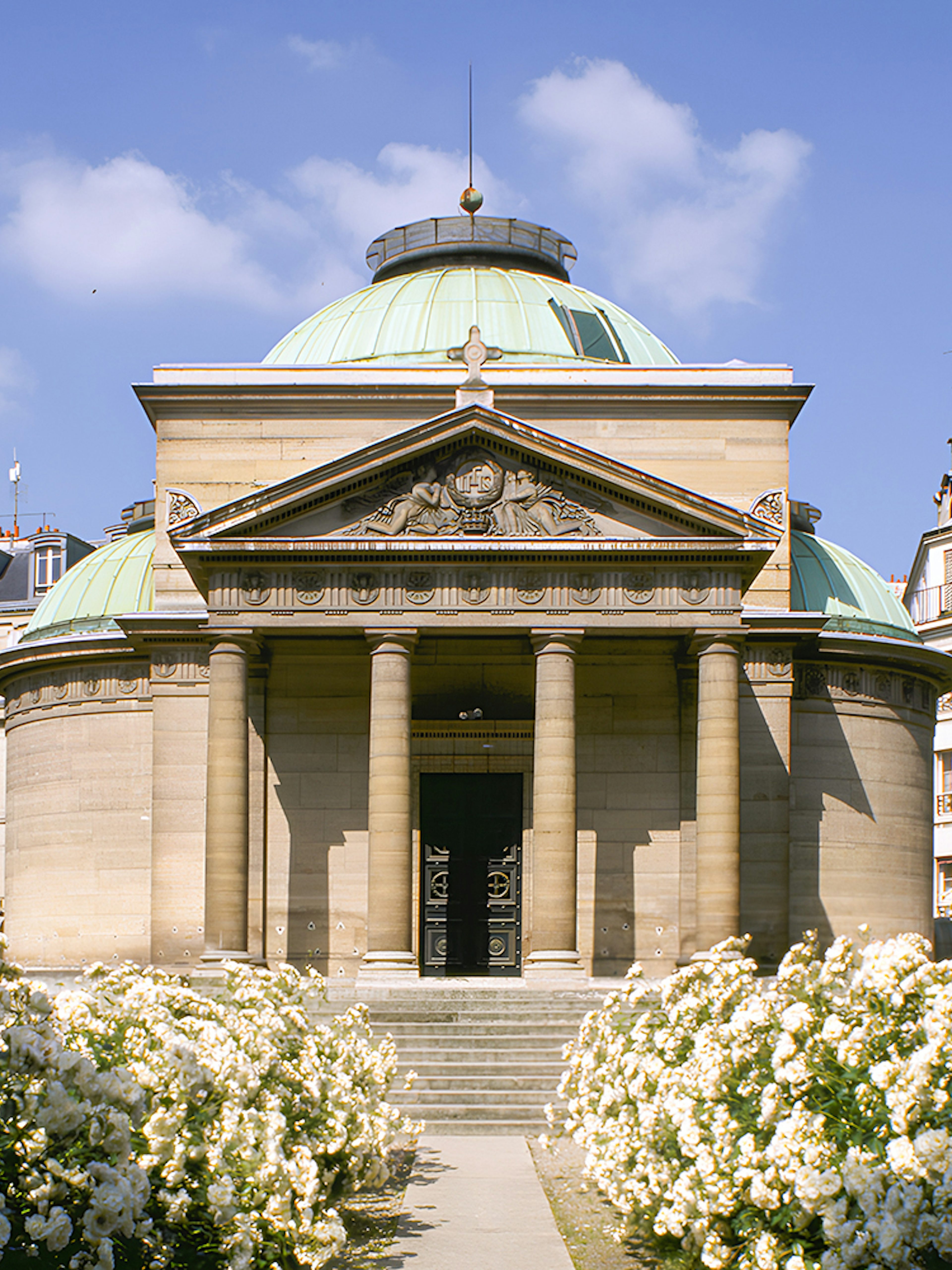 Expiatory Chapel in Paris with blooming white roses in the foreground.