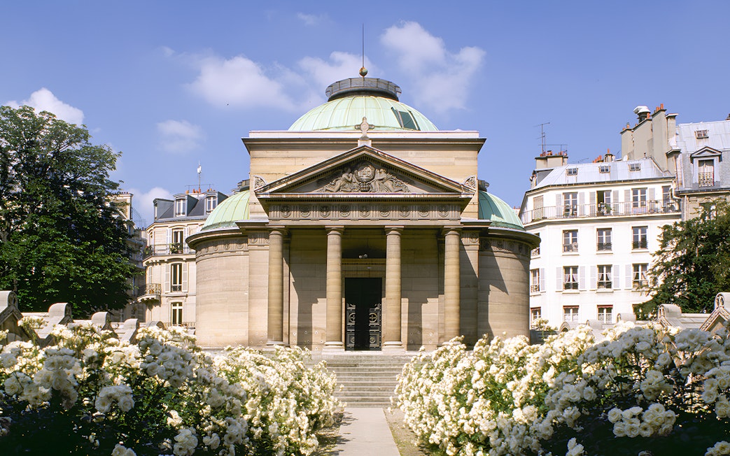 Expiatory Chapel in Paris with blooming white roses in the foreground.