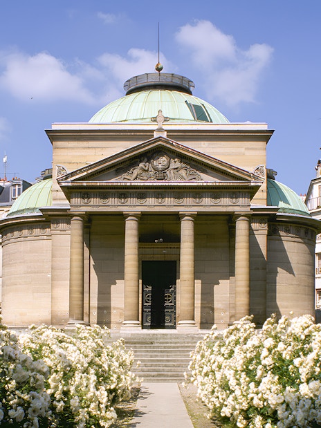 Expiatory Chapel in Paris with blooming white roses in the foreground.