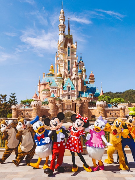 Disney characters in front of castle at Disneyland Hong Kong.
