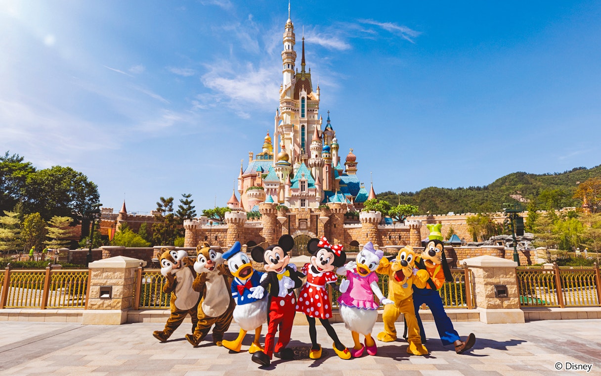 Disney characters in front of castle at Disneyland Hong Kong.