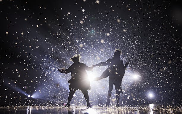 Performers on stage at Cirque du Soleil: Alegría in Seville, surrounded by confetti and lights.