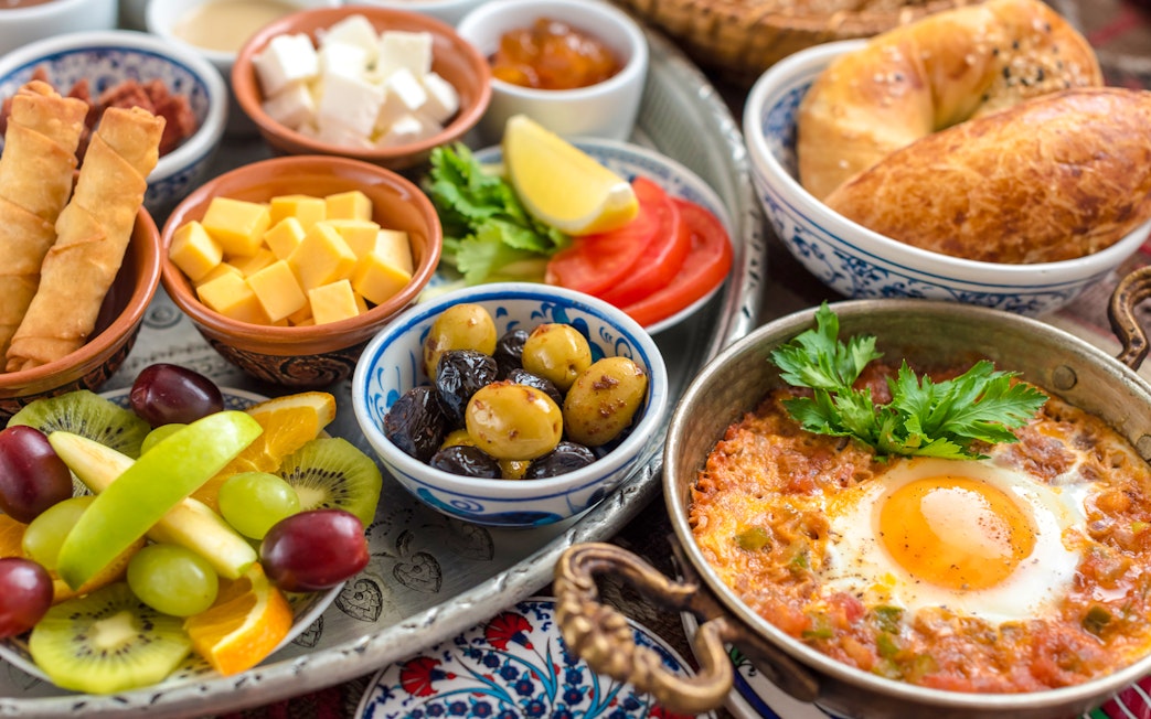 Traditional Turkish breakfast with olives, cheeses, simit, fresh fruits, and menemen in Istanbul.
