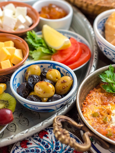 Traditional Turkish breakfast with olives, cheeses, simit, fresh fruits, and menemen in Istanbul.