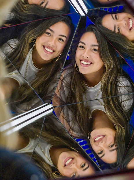 Reflections of a smiling woman in a mirrored exhibit at The TUBE.
