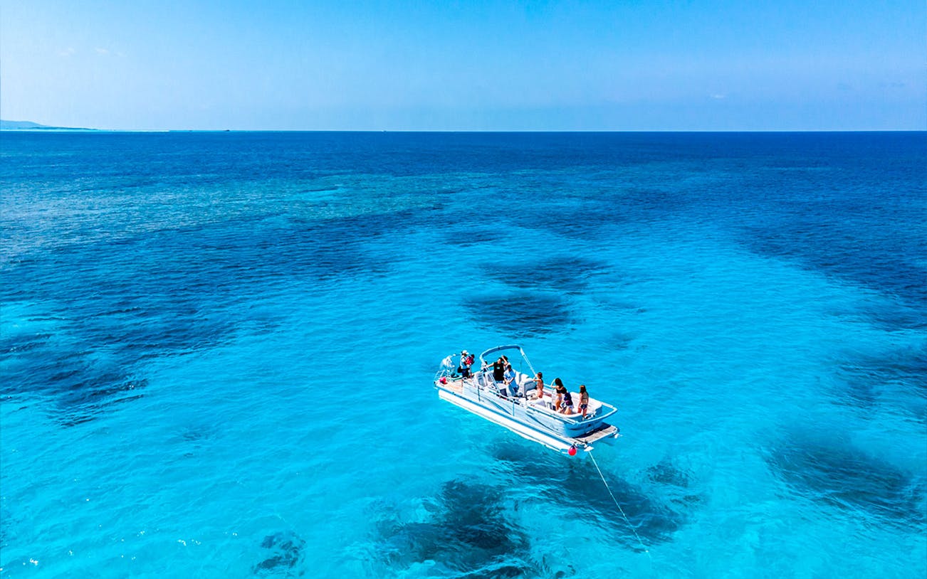 Cruise boat on Ishigaki Island's turquoise sea with passengers ready for snorkeling.