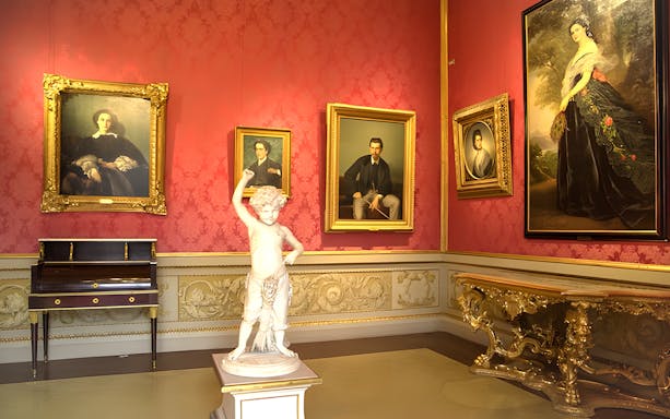 Palazzo Pitti interior with classical paintings and a marble statue in Florence.
