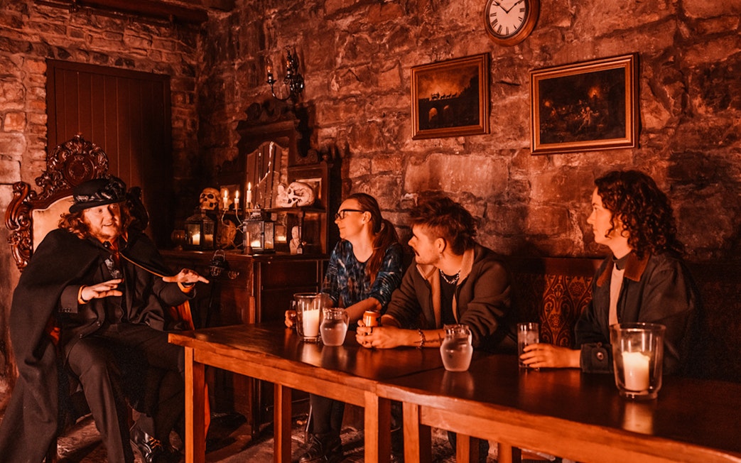 Edinburgh ghost tour guide narrating stories to visitors in a dimly lit underground room.