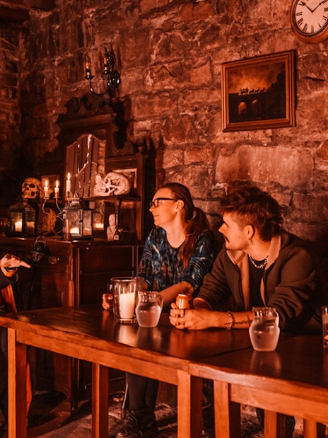 Edinburgh ghost tour guide narrating stories to visitors in a dimly lit underground room.