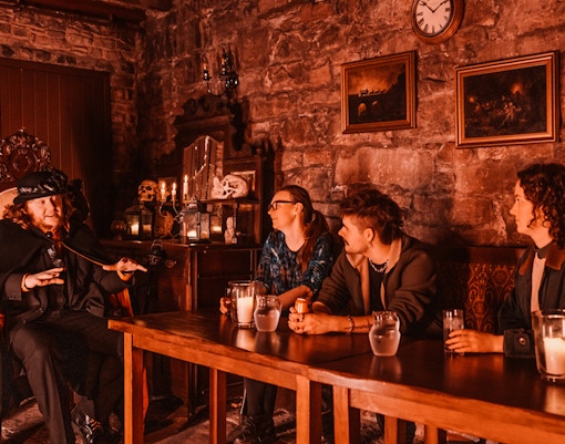 Edinburgh ghost tour guide narrating stories to visitors in a dimly lit underground room.