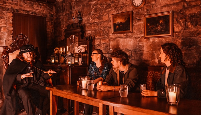 Edinburgh ghost tour guide narrating stories to visitors in a dimly lit underground room.