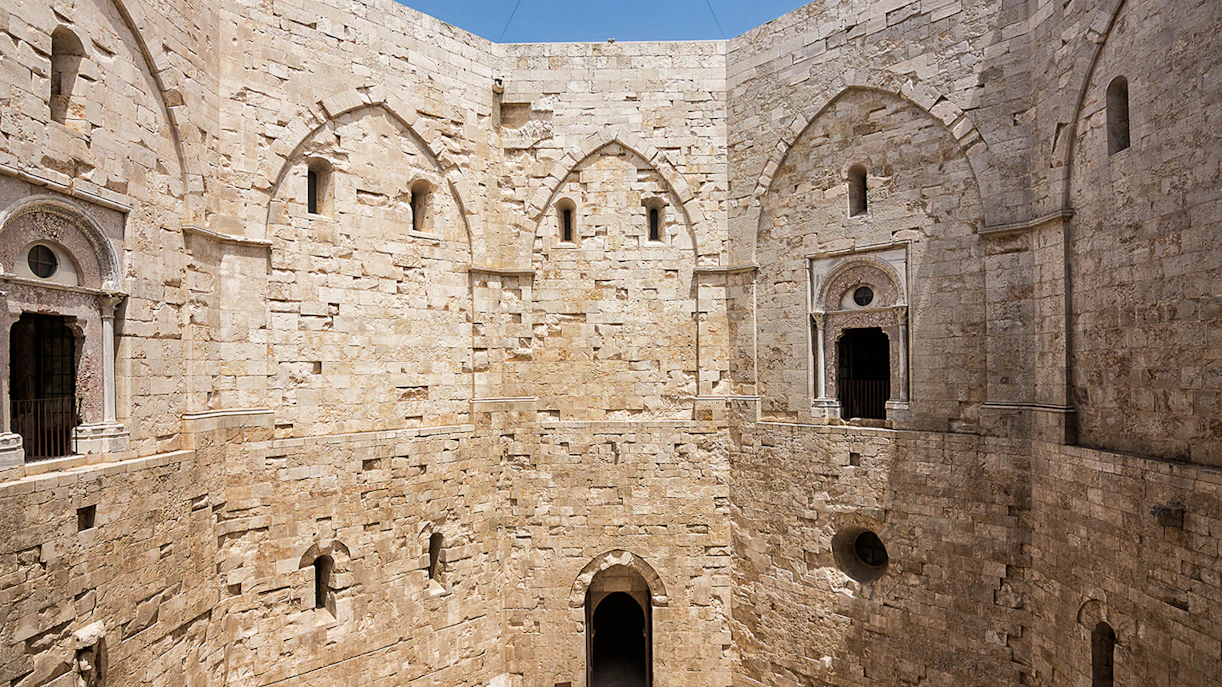 Castel del Monte interior stone walls with arched doorways and windows.