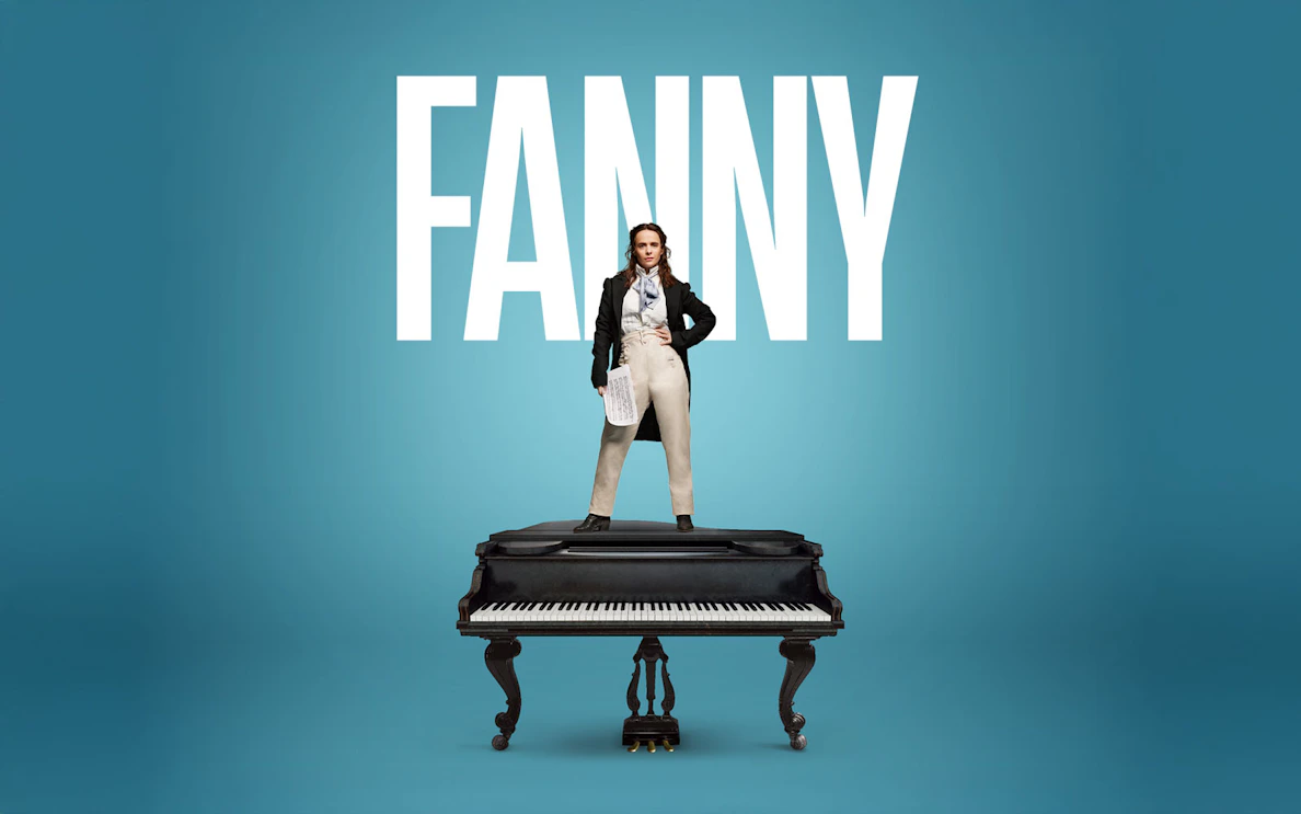 Performer standing on a grand piano in London theater.