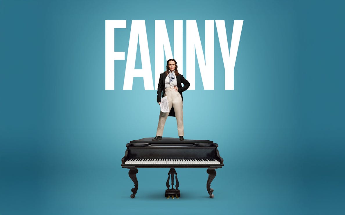 Performer standing on a grand piano in London theater.