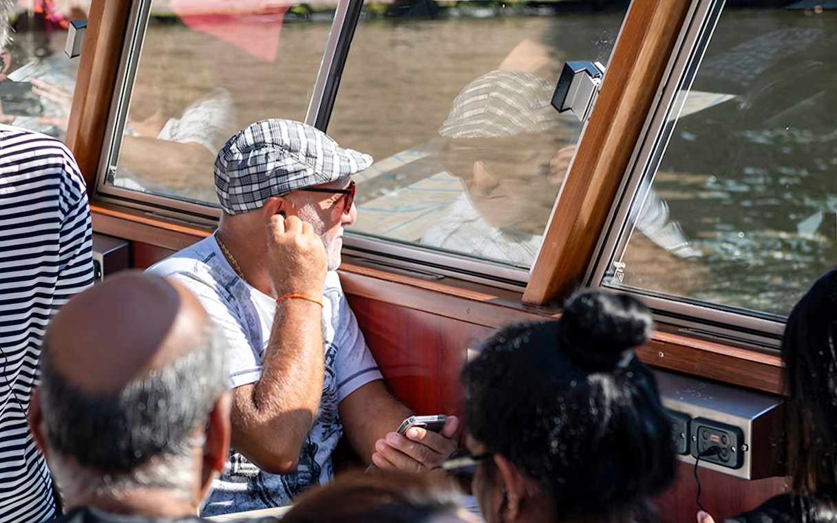 Passengers enjoying Amsterdam canal cruise through boat window.