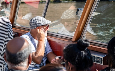 Passengers enjoying Amsterdam canal cruise through boat window.