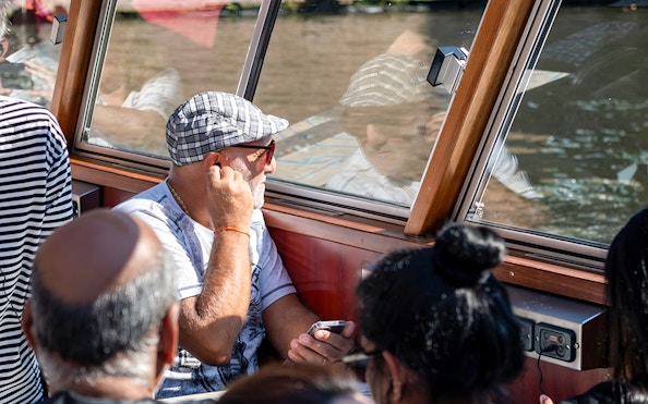 Passengers enjoying Amsterdam canal cruise through boat window.