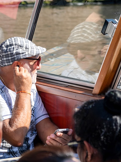 Passengers enjoying Amsterdam canal cruise through boat window.