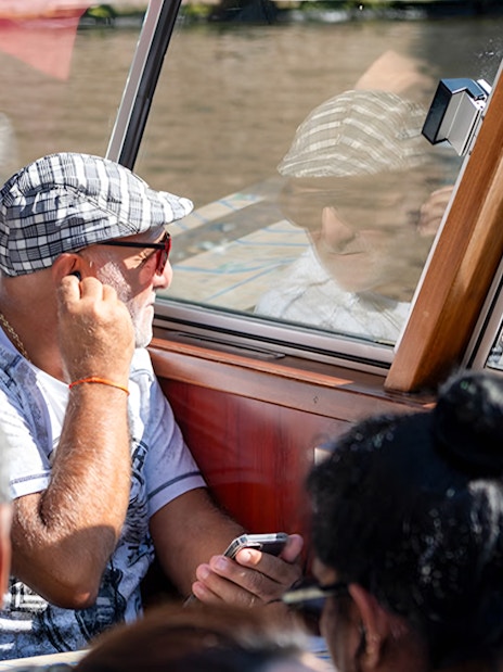 Passengers enjoying Amsterdam canal cruise through boat window.