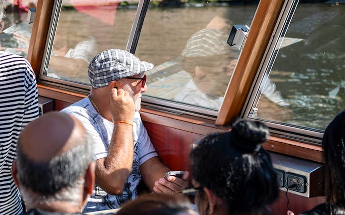 Passengers enjoying Amsterdam canal cruise through boat window.