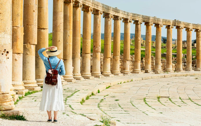 Young woman tourist exploring ancient Roman columns in Jerash, Jordan.