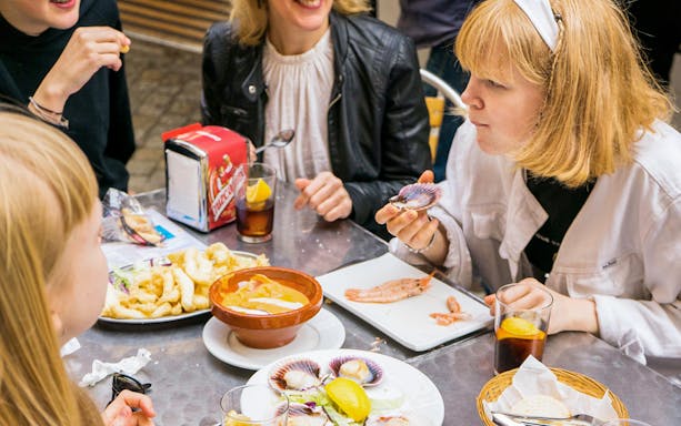 Tapas tasting tour in Seville with people enjoying seafood and drinks at a table.