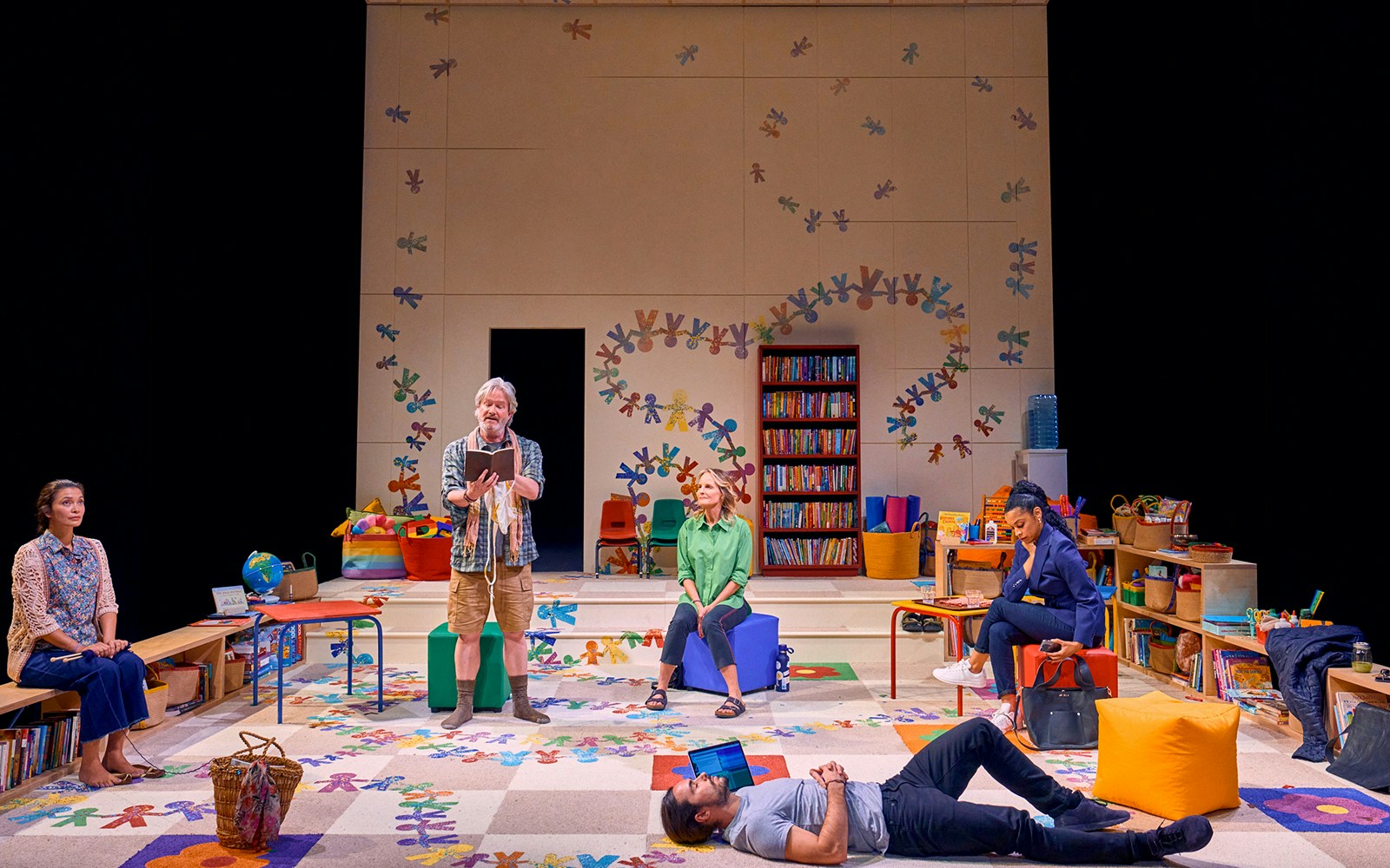 Actors performing a scene from "Eureka Day" in a colorful classroom setting.