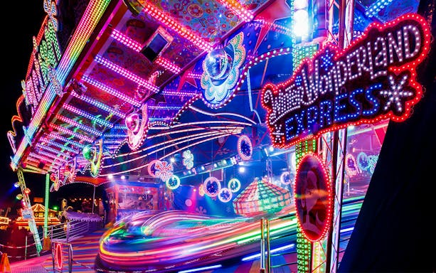 Colorful amusement ride at Winter Wonderland with vibrant lights and spinning motion.