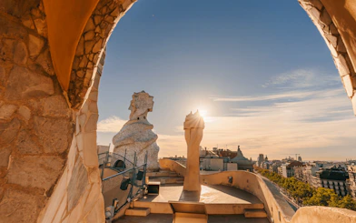 La Pedrera Casa Mila terrace view at sunrise, Barcelona skyline in background.
