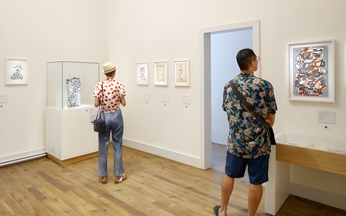 Visitors viewing modern art at Beaulieu-en-Rouergue Abbey exhibition.