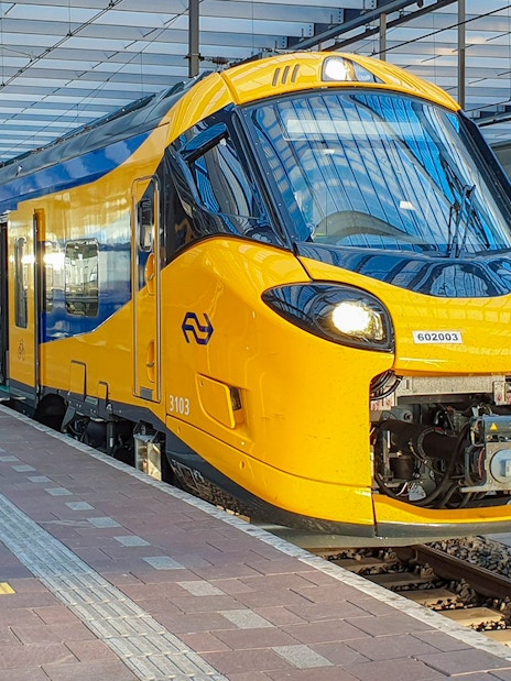NS train at Schiphol Airport platform, ready for departure.