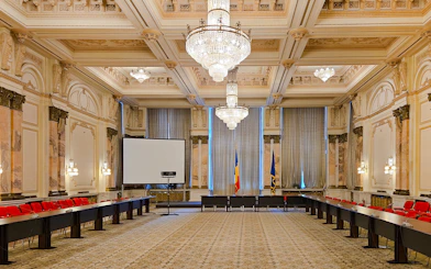 Palace of Parliament conference room with chandeliers and Romanian flags.